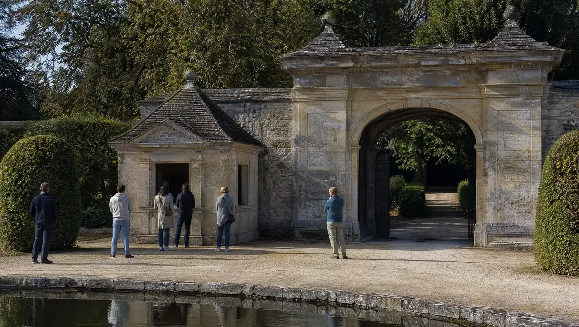 Visitors at a small ticket kiosk beside a stone gatehouse